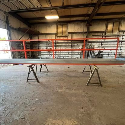 A large metal railing is sitting on top of a wooden trestle in a warehouse.