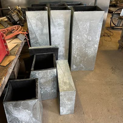 A bunch of metal planters are sitting on the floor in a room.