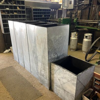 A row of metal planters are sitting next to each other in a room.