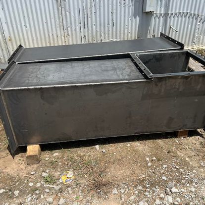 A large metal container is sitting on top of a dirt field.