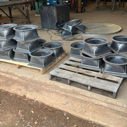 A wooden pallet is sitting on the ground next to a pile of metal pipes.