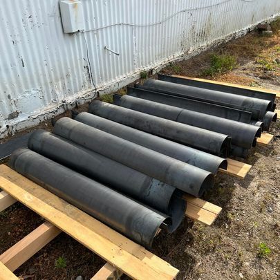 A bunch of metal pipes are stacked on top of each other on a wooden pallet.