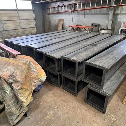 A bunch of metal pipes are stacked on top of each other in a garage.