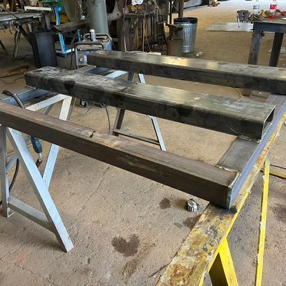 A metal bench is sitting on top of a wooden trestle in a workshop.