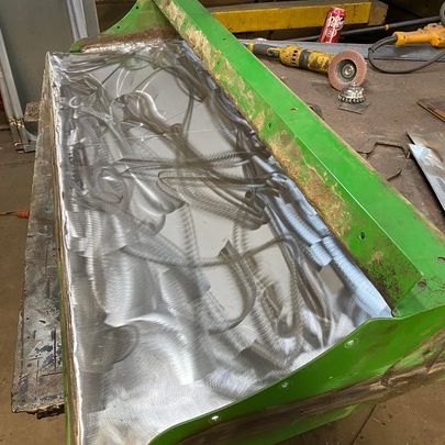 A green bench is sitting on top of a wooden table next to a grinder.