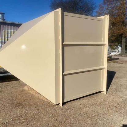 A large white container is sitting on top of a dirt field.