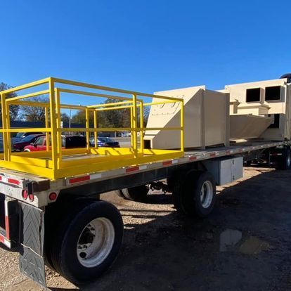 A flatbed truck with a yellow railing on the back