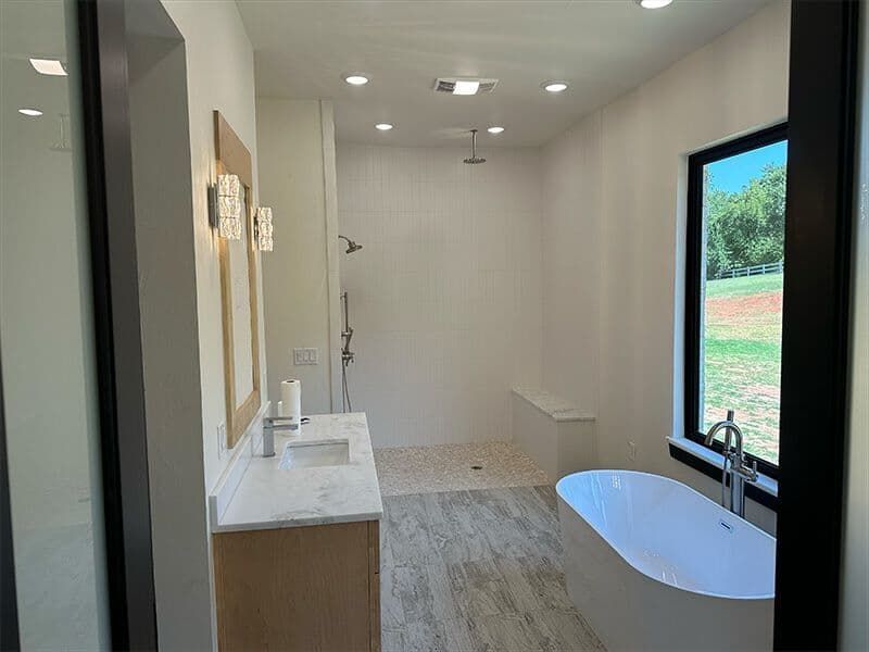 A modern bathroom featuring a freestanding tub, a walk-in shower with a glass wall, and a wooden vanity under a mirror.