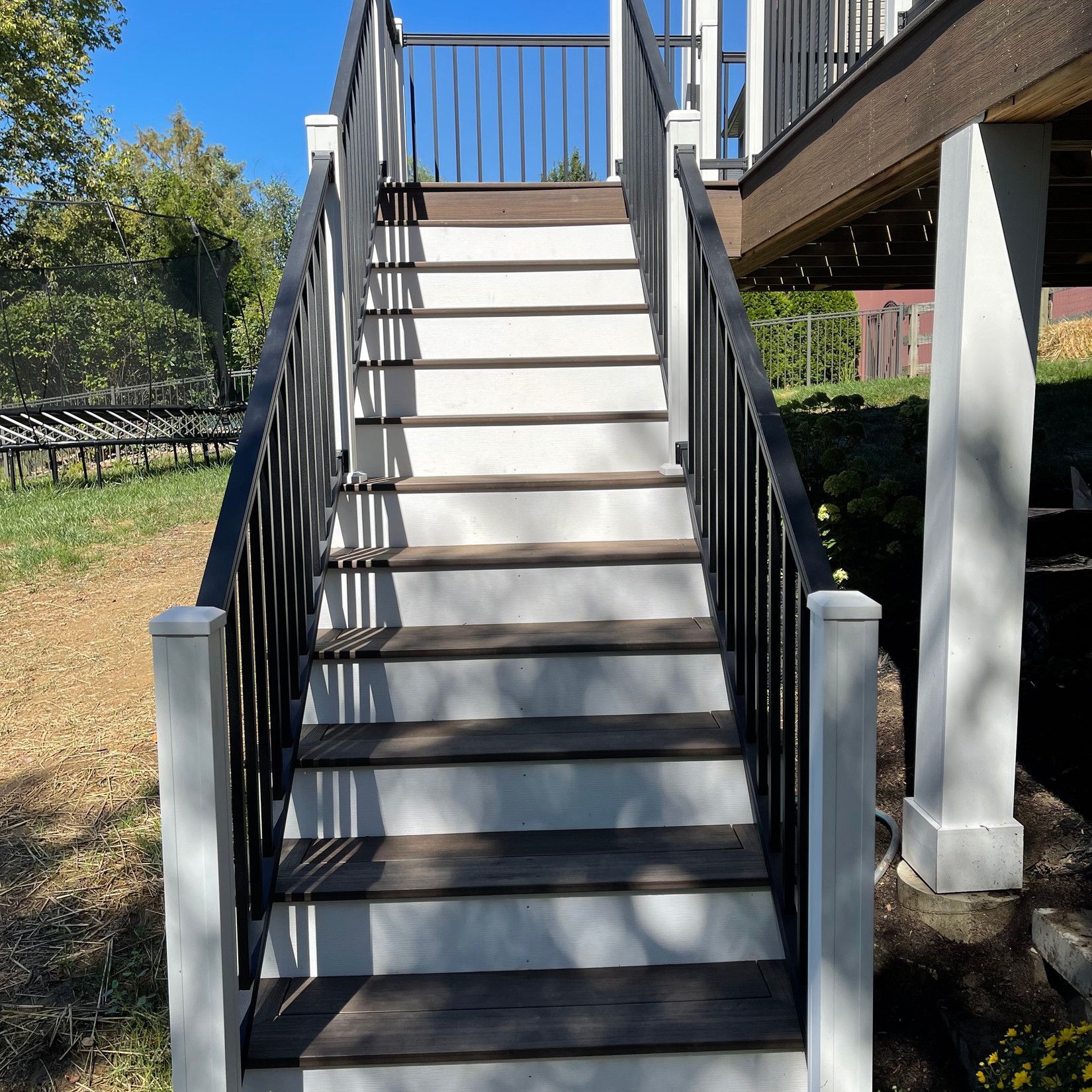 A set of stairs leading up to a deck with a black railing
