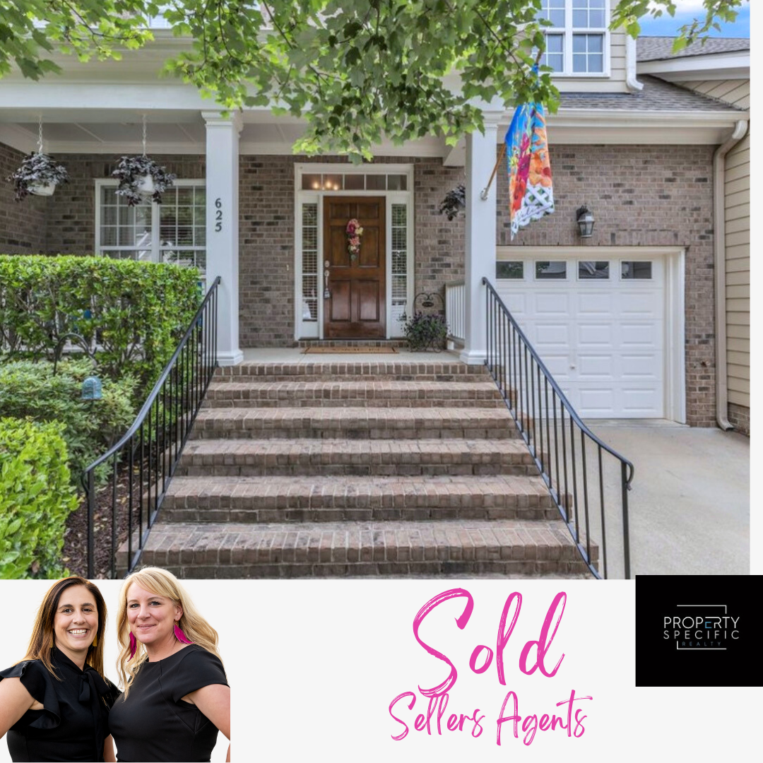 A brick home with a white garage and front steps. Two women, real estate agents, with