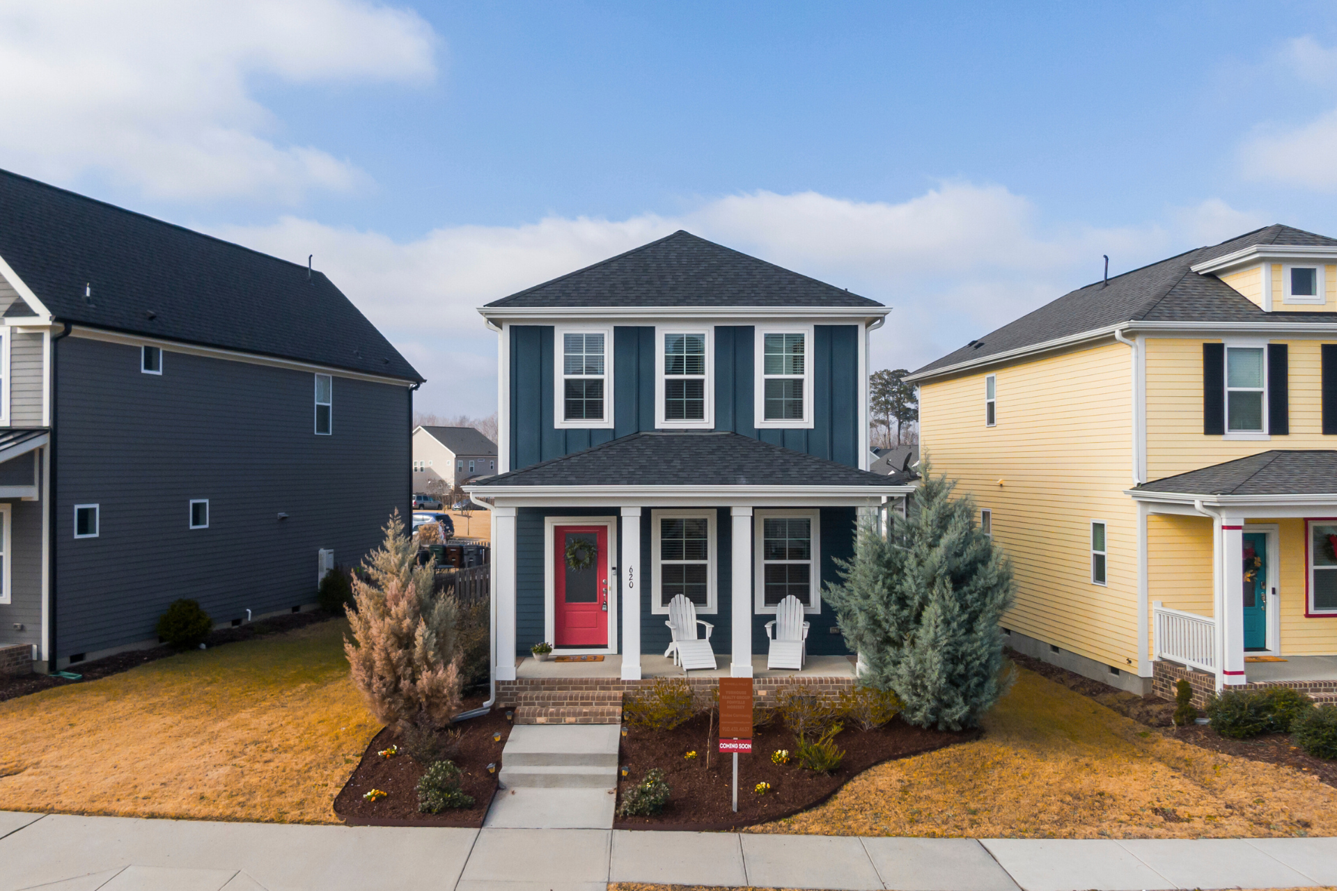 Two-story blue house with red door; flanked by a gray house on the left, and a yellow house on the right.