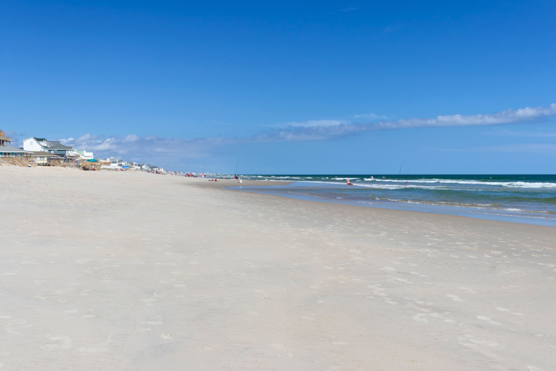 A beach with a lot of sand and a blue sky on a sunny day.