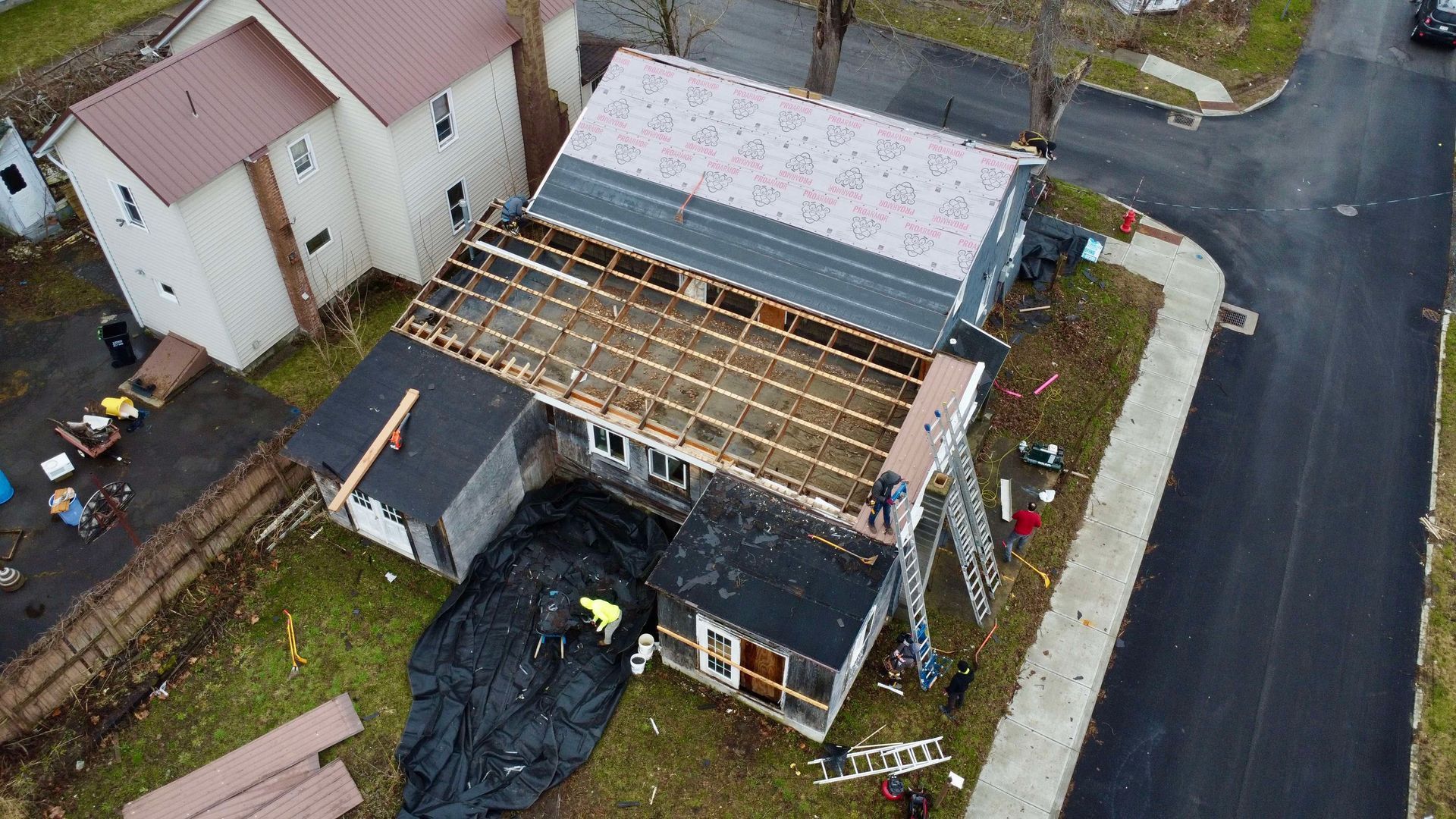 An aerial view of a house under construction with a roof being installed