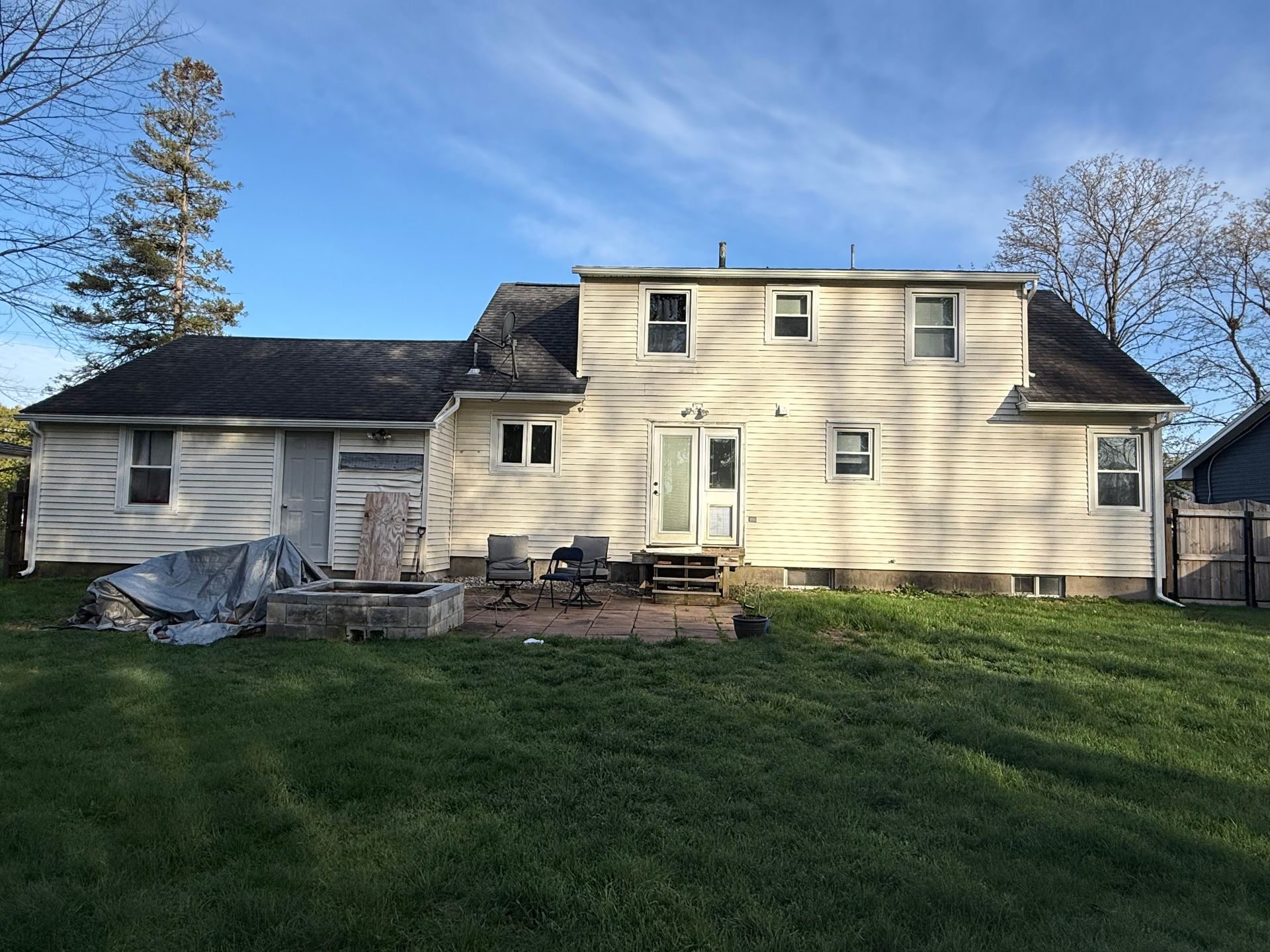 The back of a house with a fire pit in the backyard