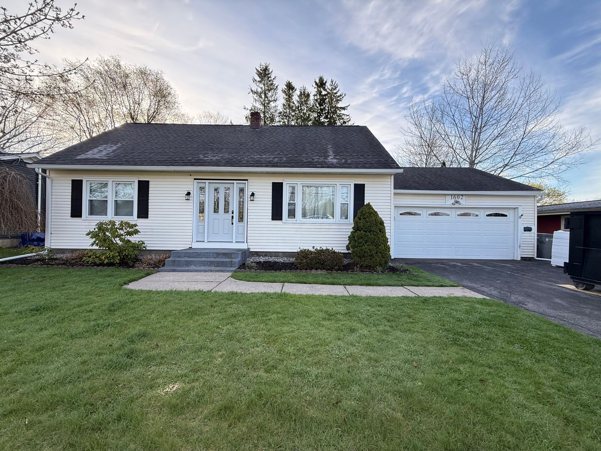 A white house with a black roof and a white garage door