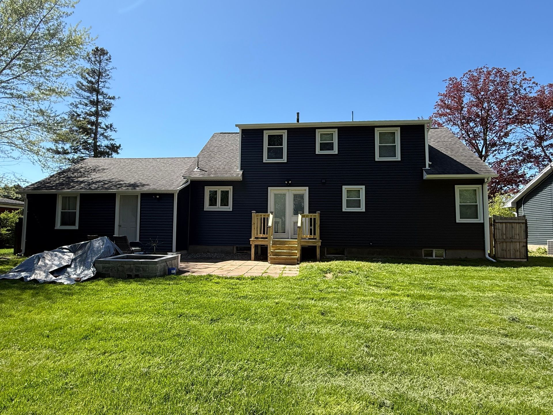 The back of a black house with a large lawn in front of it