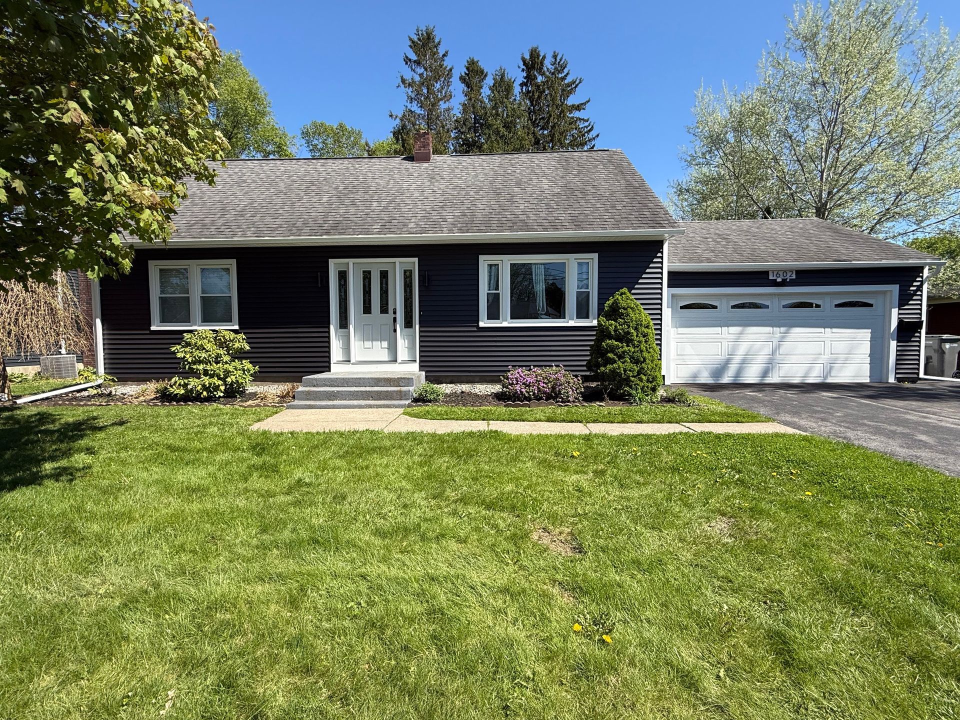 A black and white house with a large lawn in front of it
