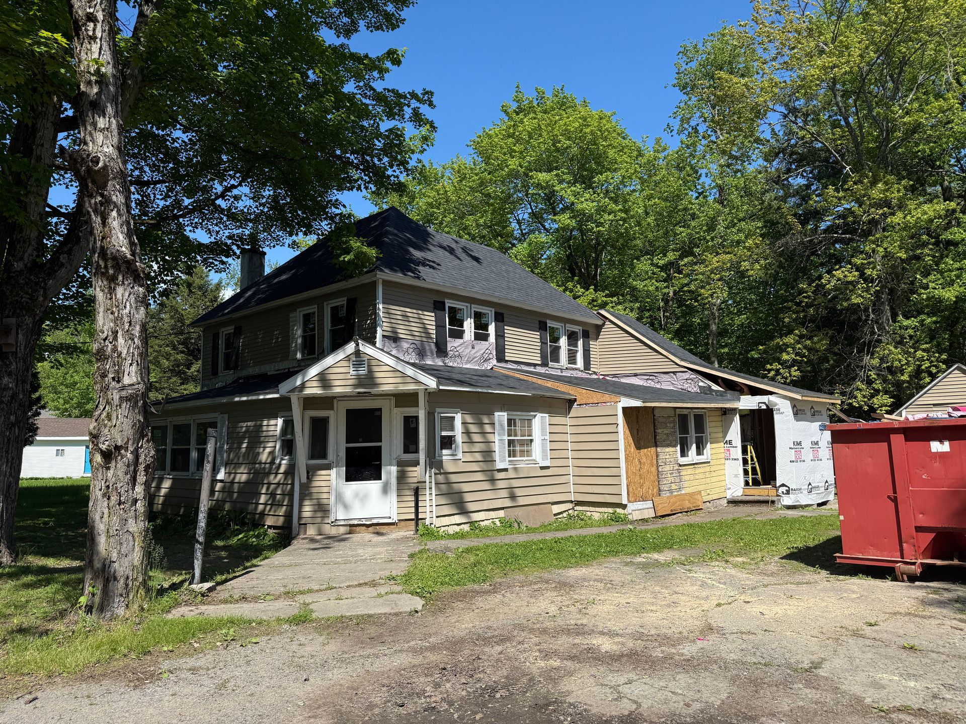 A large house with a red dumpster in front of it
