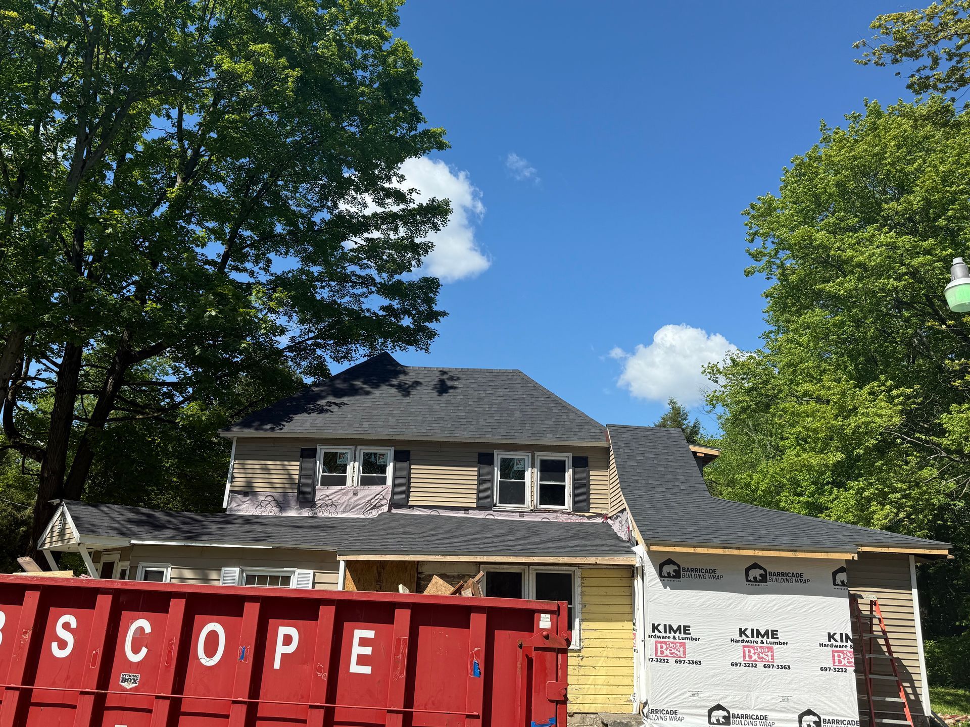 A house under construction with a red dumpster in front of it that says scope