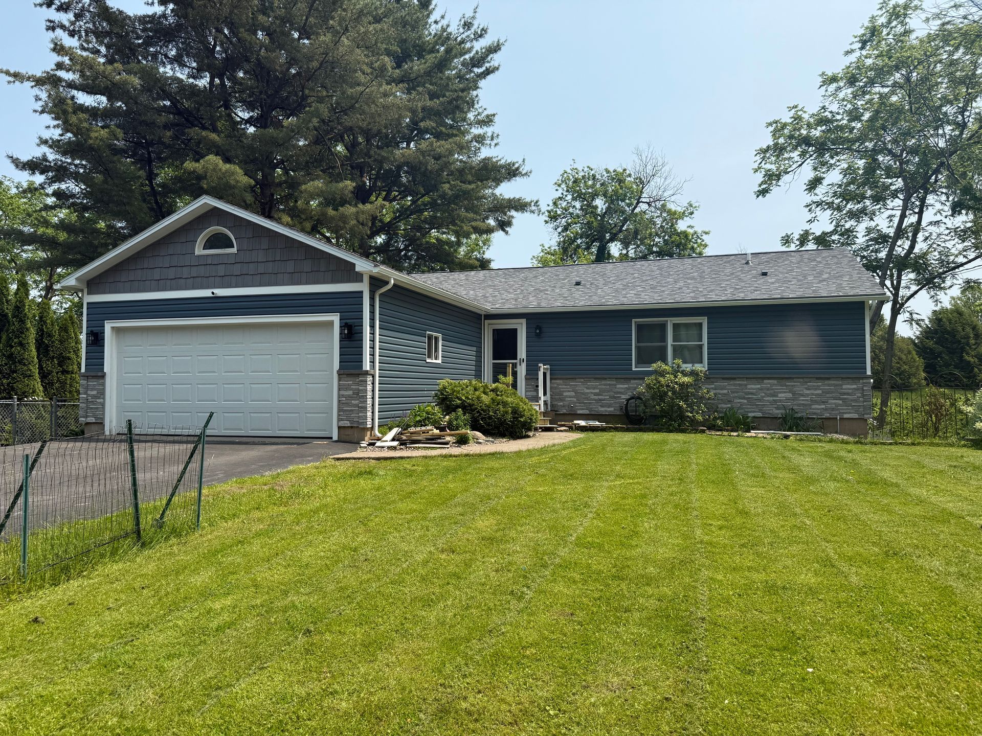 A house with a garage and a large lawn in front of it