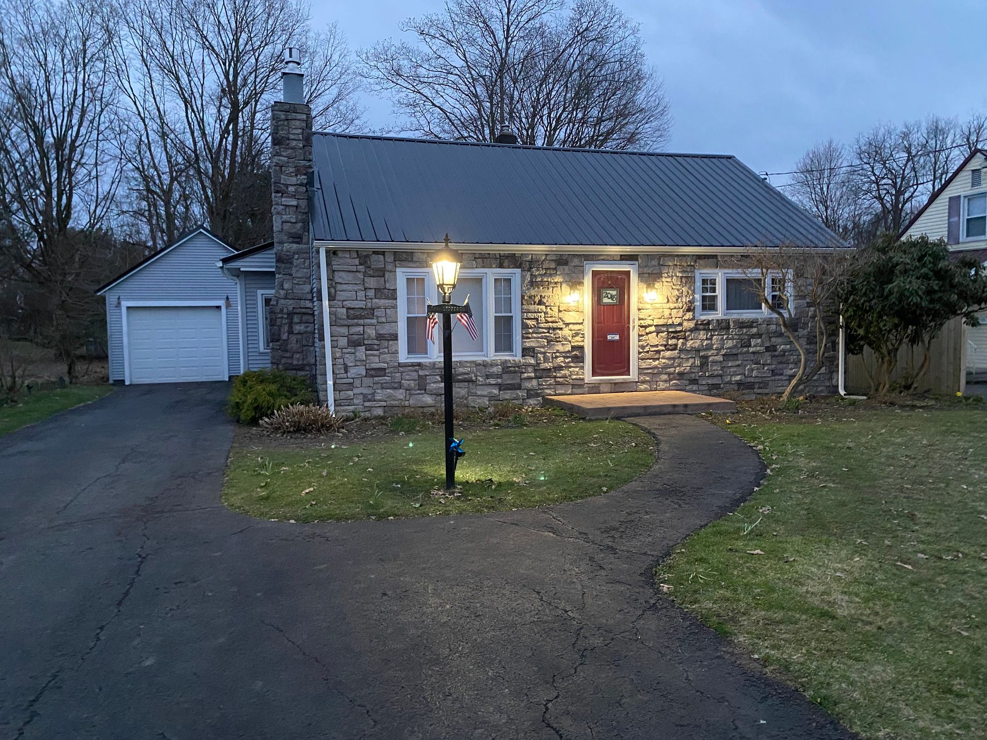 A small stone house with a red door is lit up at night