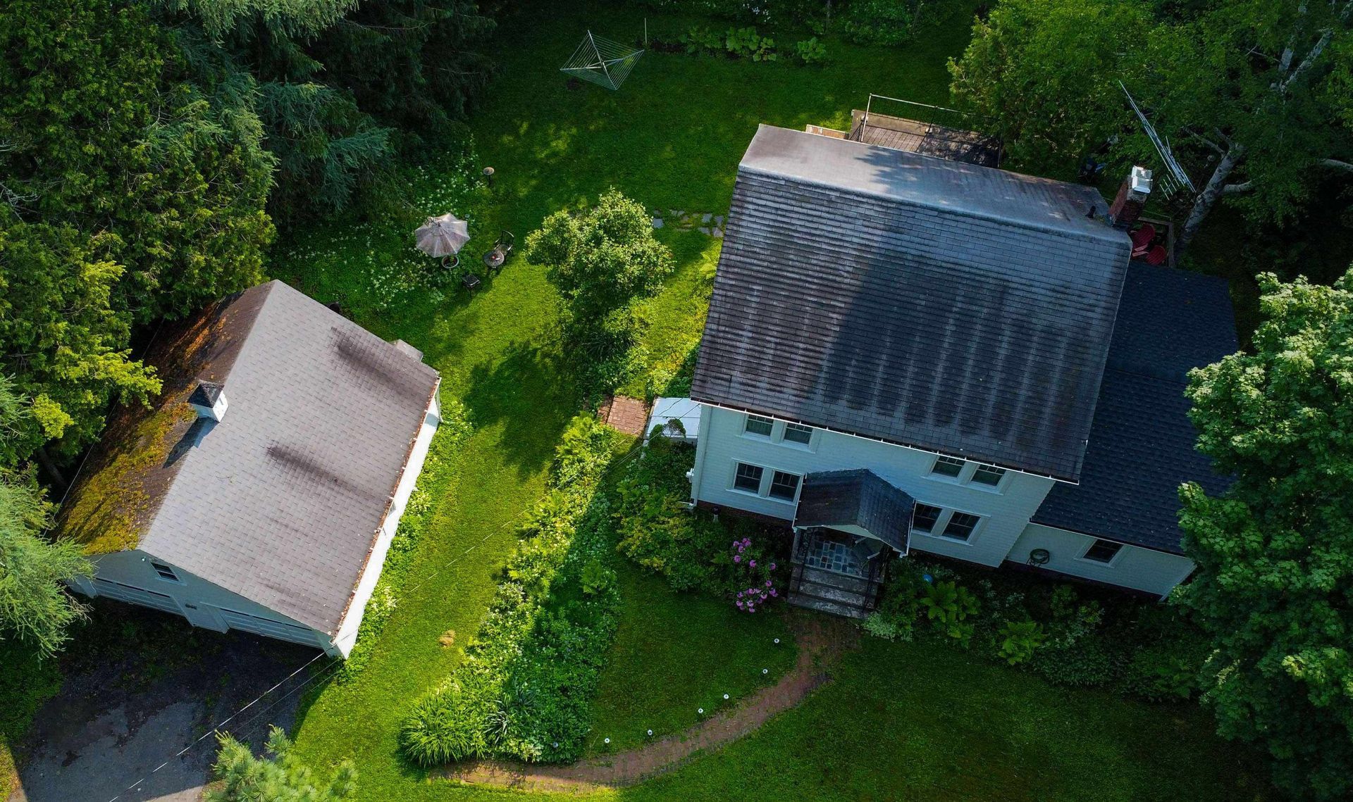 An aerial view of a house and a garage surrounded by trees