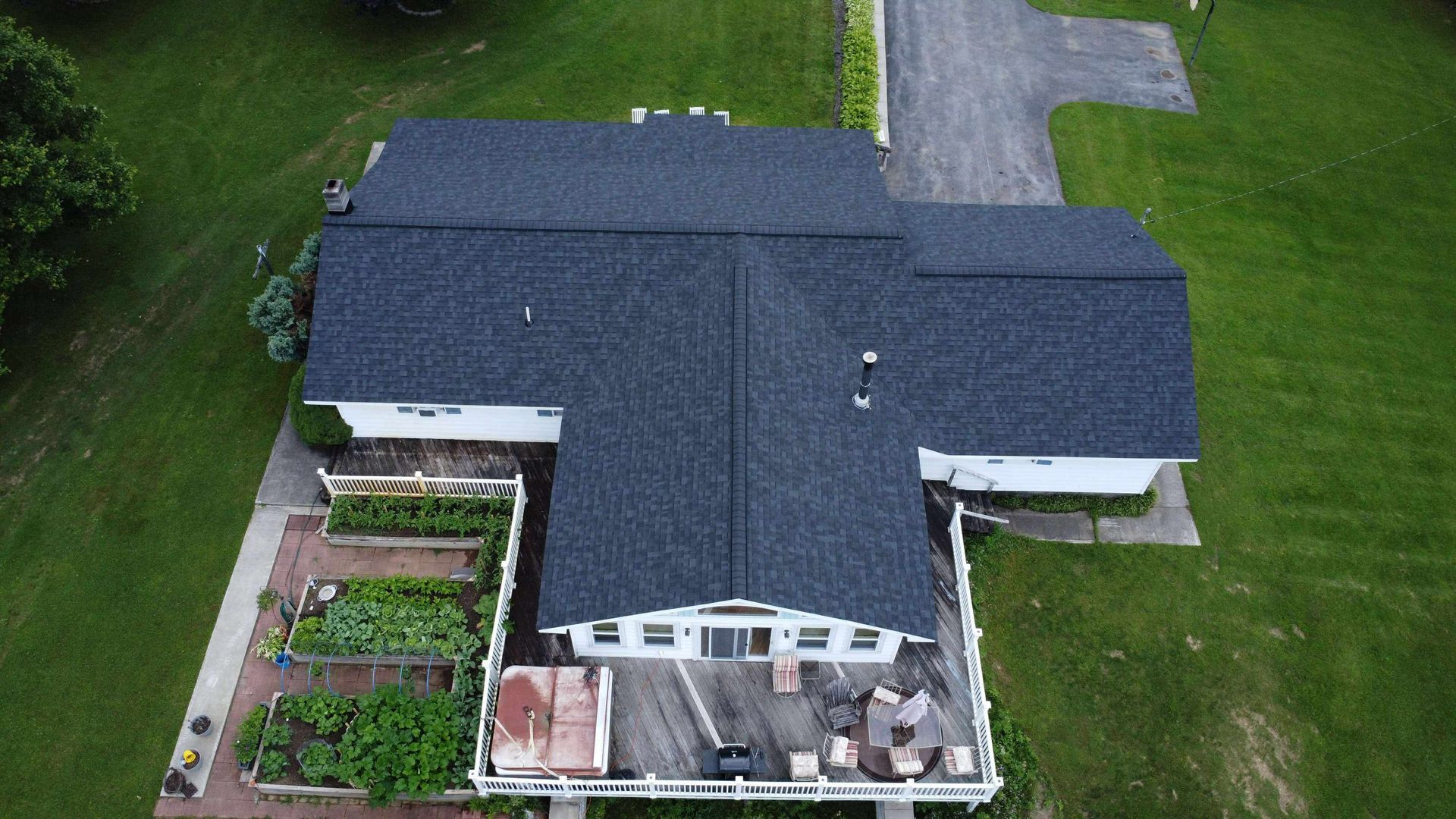 Aerial view of a brown-roofed house with a swimming pool in the yard.