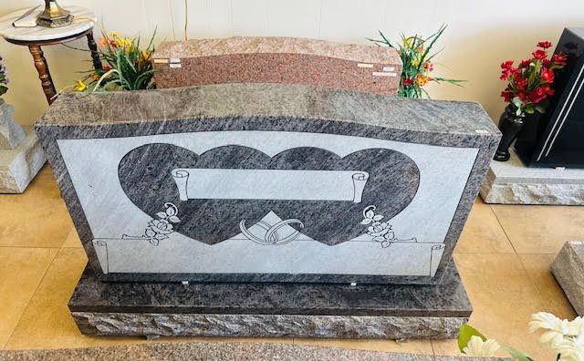 A gravestone with two hearts on it is sitting on a tiled floor.