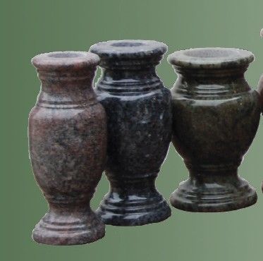 A woman is putting flowers in a vase on a table.