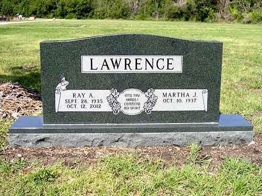 A gravestone for lawrence is sitting in the middle of a grassy field.