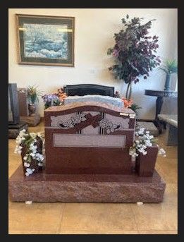 A red gravestone with flowers on it is in a room with a picture on the wall.