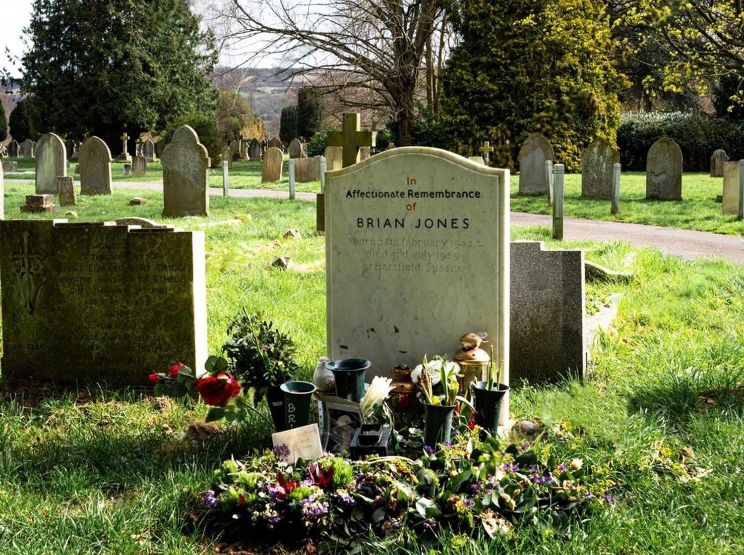 A gravestone for walden in a cemetery with flowers in a vase.