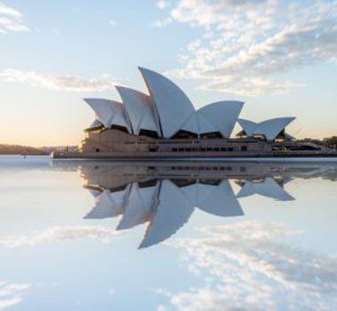 The sydney opera house is reflected in the water.