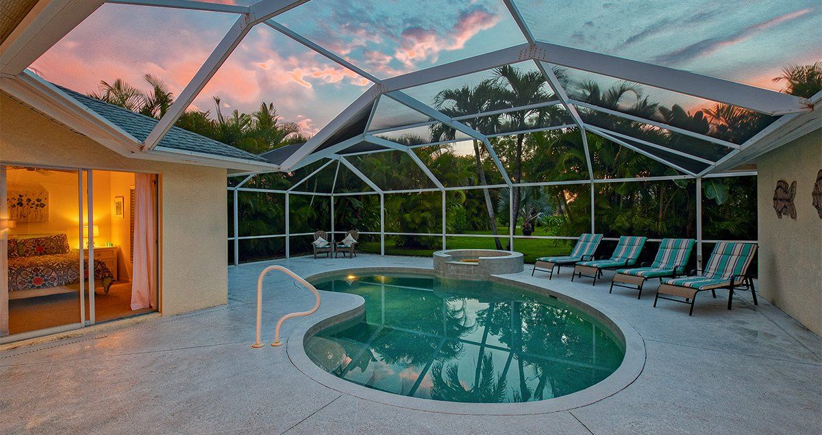 Swimmingpool mit Sonnenliegen und Stühlen bei Sonnenuntergang bei Naples Lake View, Florida