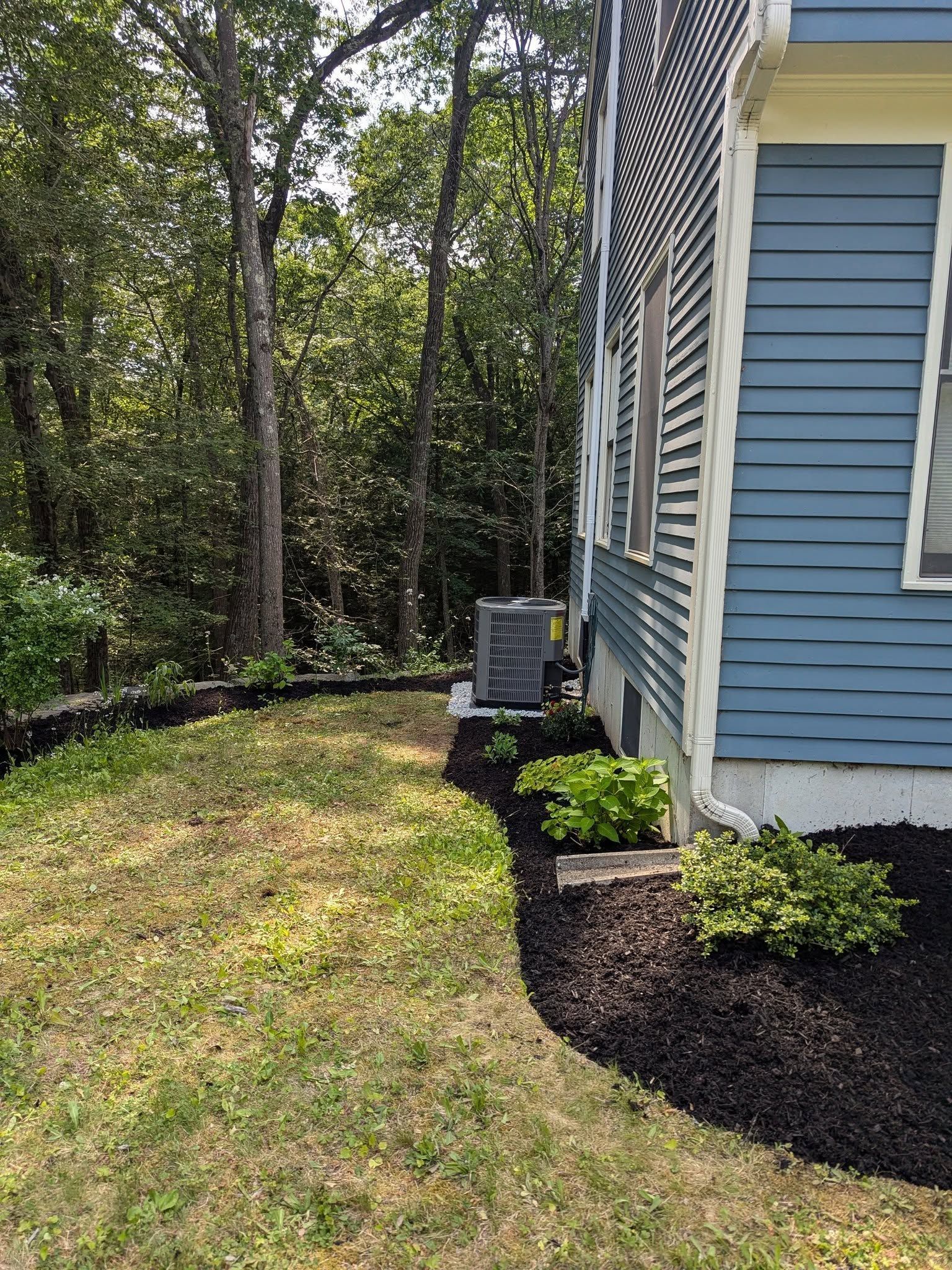 A blue house with a lawn in front of it and trees in the background.