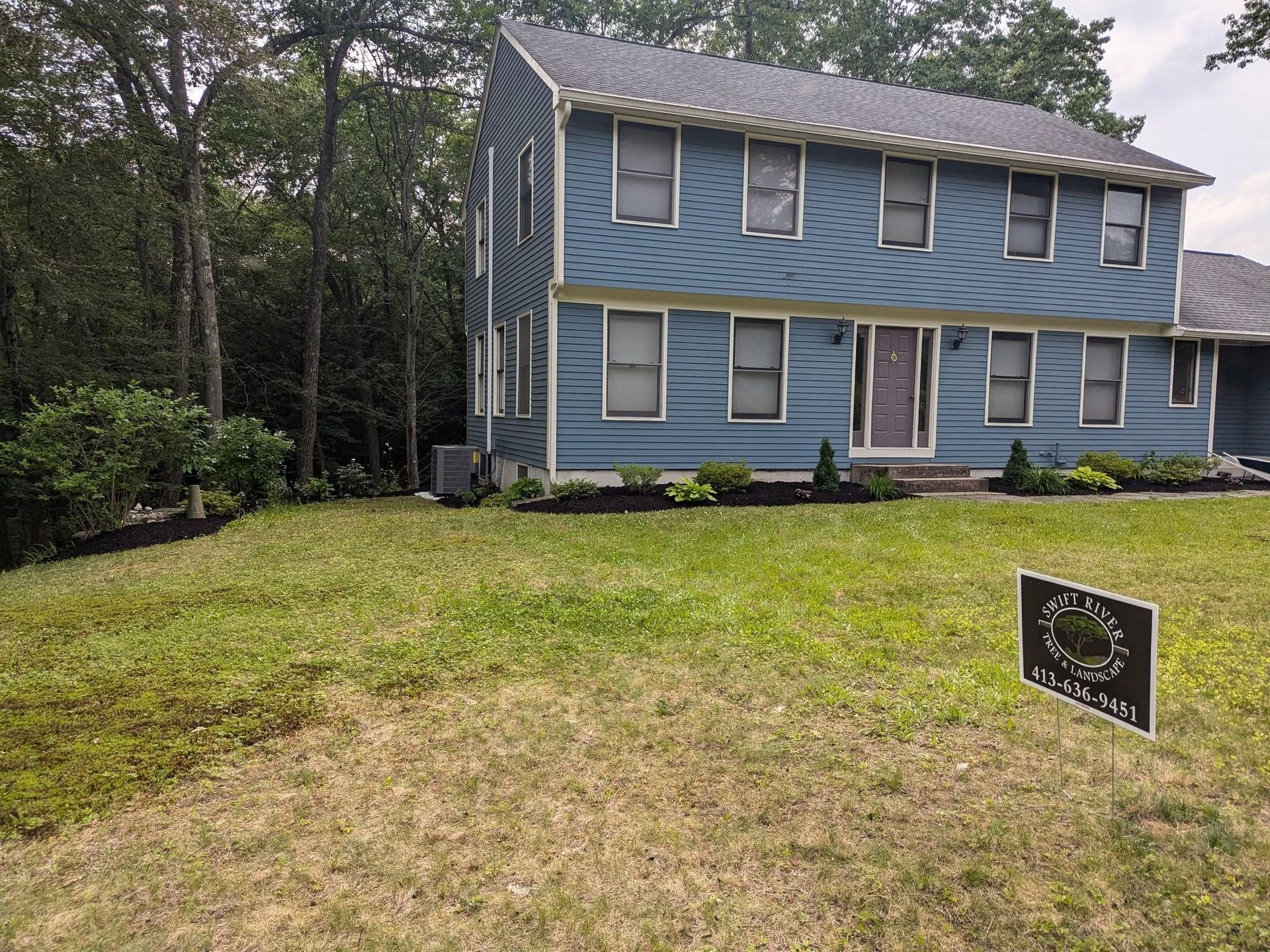 A blue house with a sign in front of it.