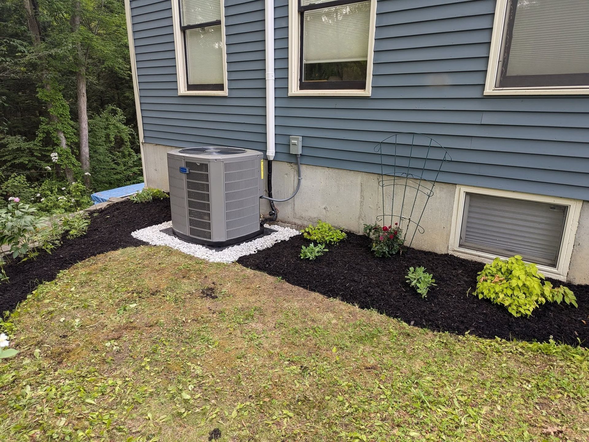 An air conditioner is sitting in the backyard of a house.