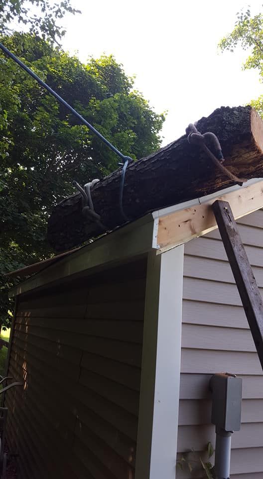 A large log is sitting on the roof of a house.
