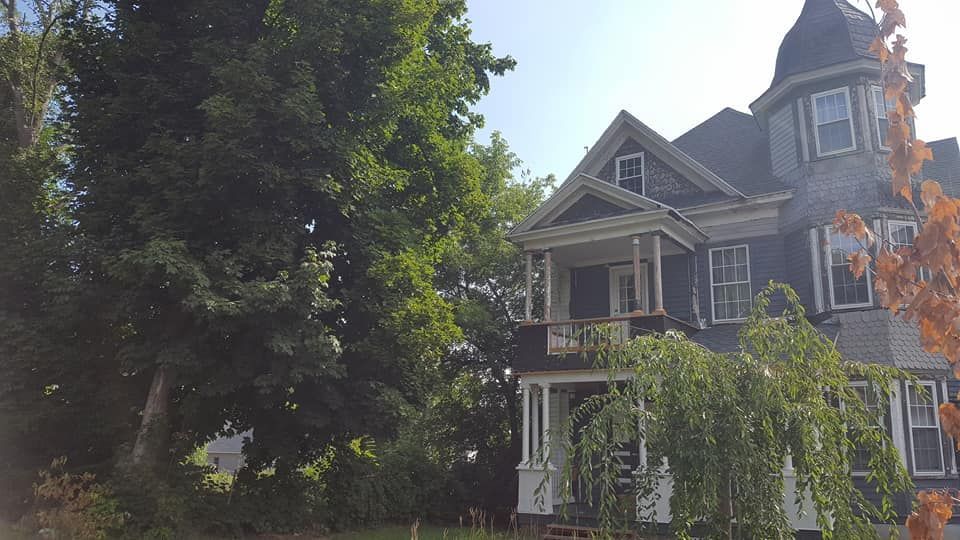 A large house is surrounded by trees on a sunny day