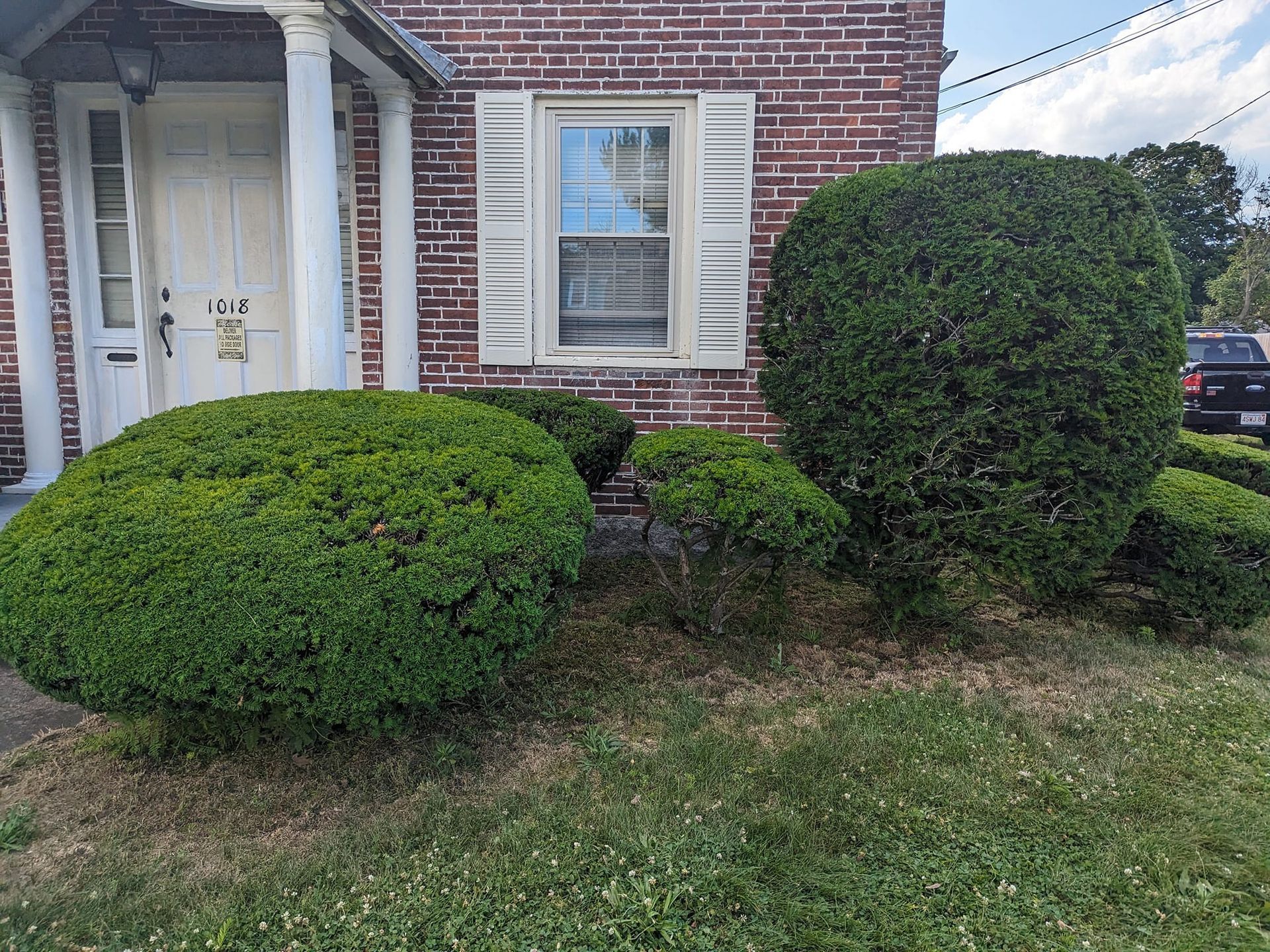 A brick house with a lot of bushes in front of it.