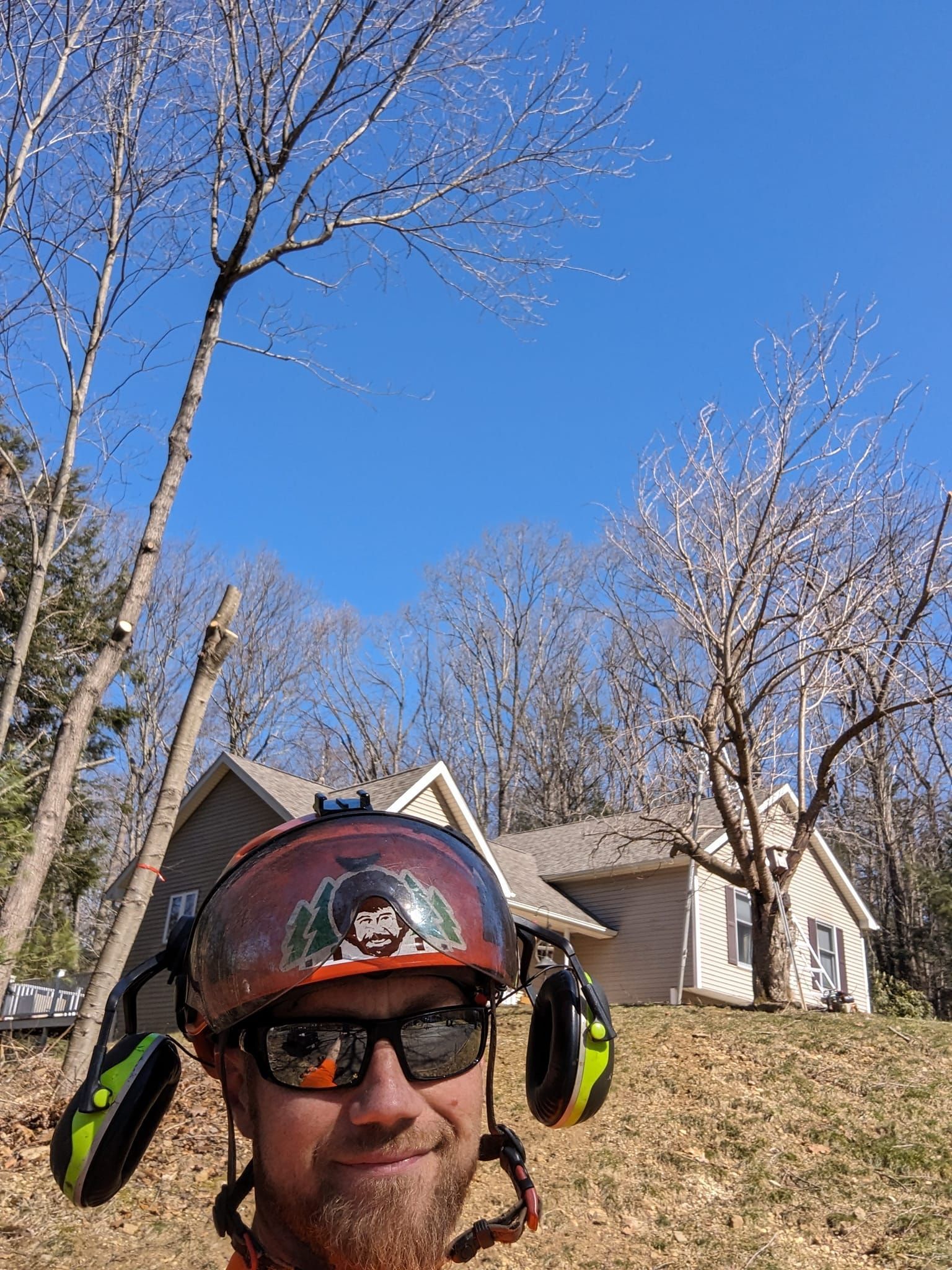 A man wearing a helmet and sunglasses is standing in front of a house.