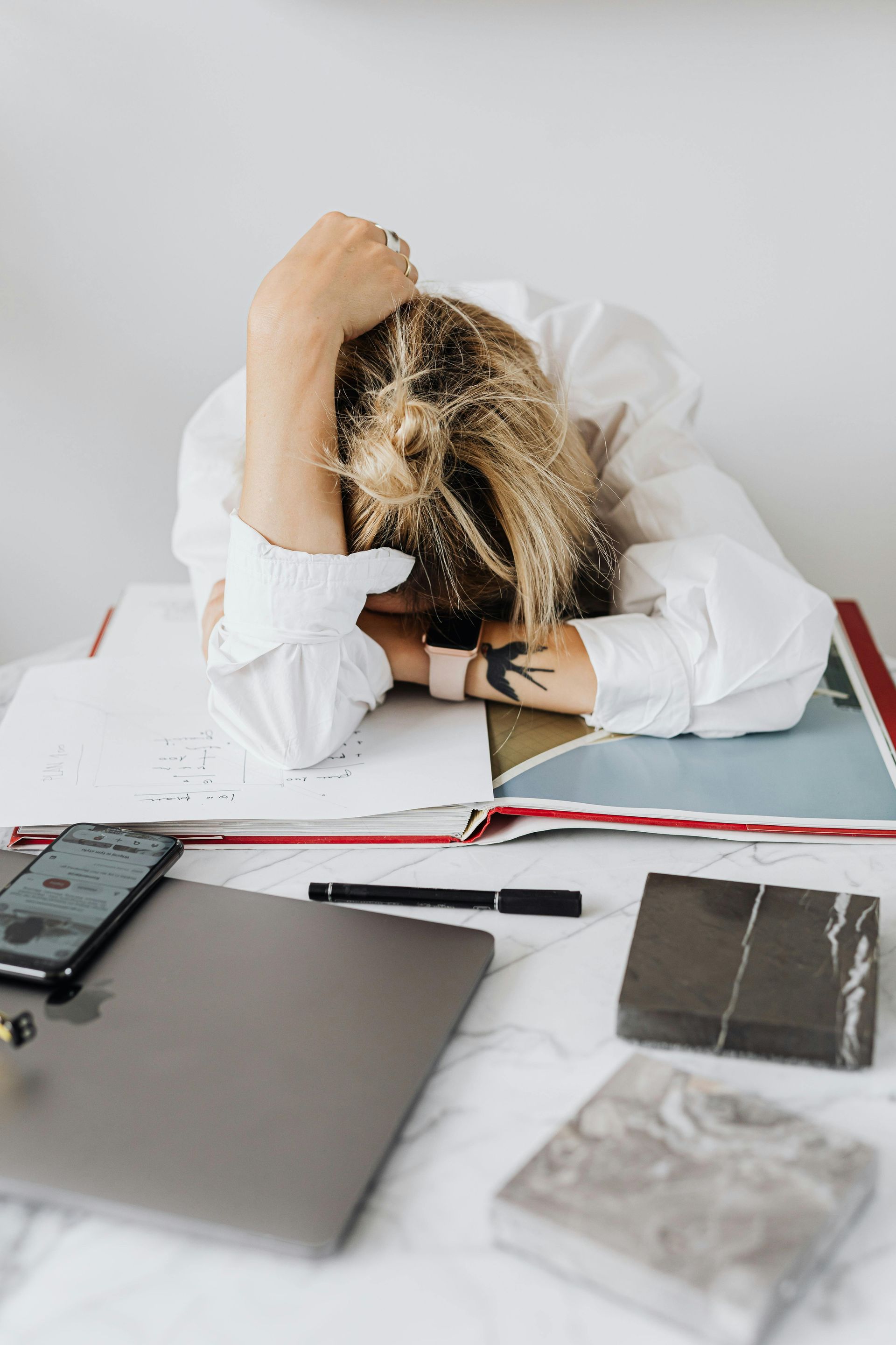 Woman at work with her head down, burned out from work.