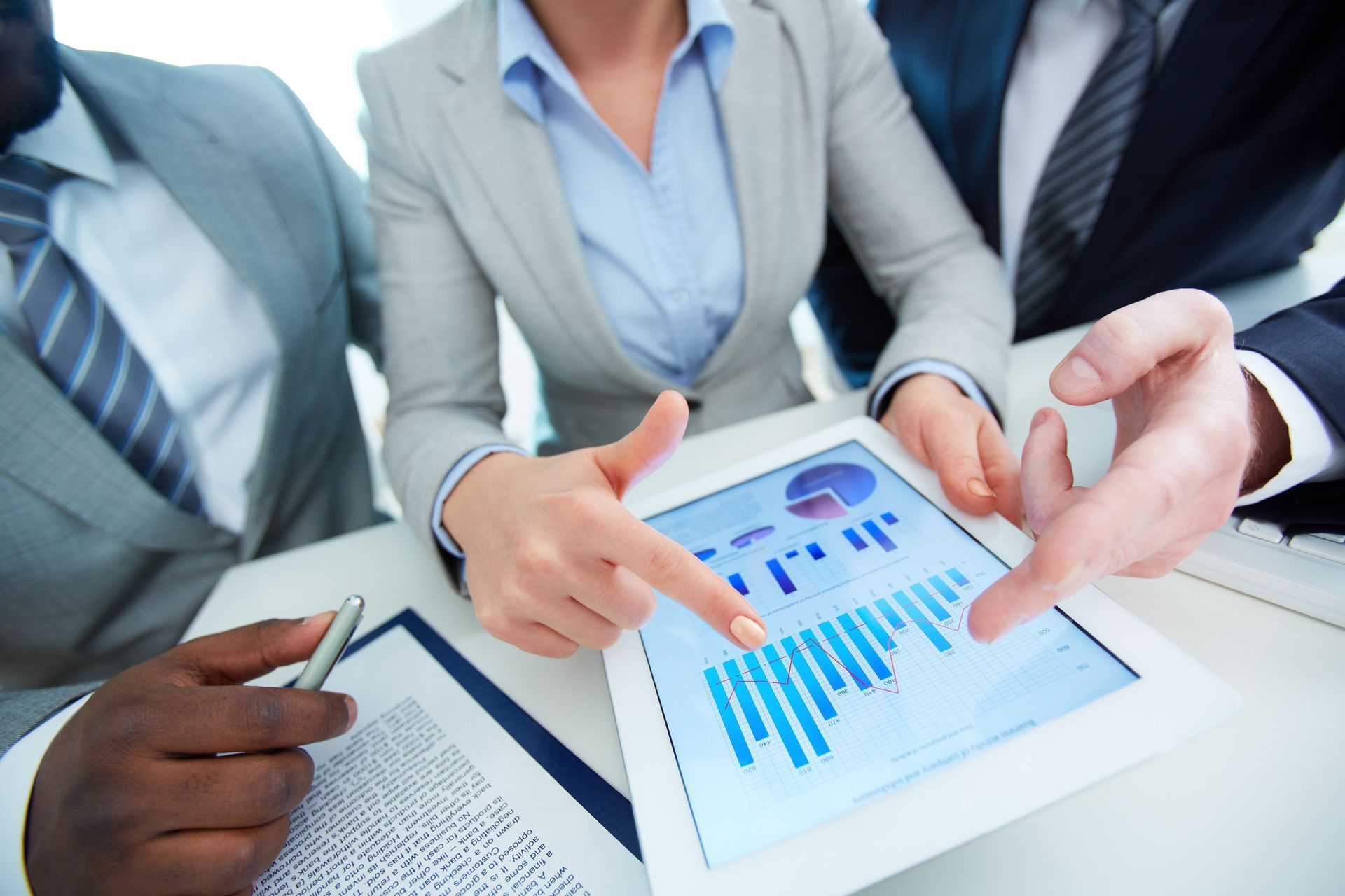 Hands pointing at charts on a tablet during a business data analysis meeting. Hands pointing at charts on a tablet during a business data analysis meeting.