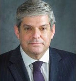 A man in a suit and tie is looking at the camera.