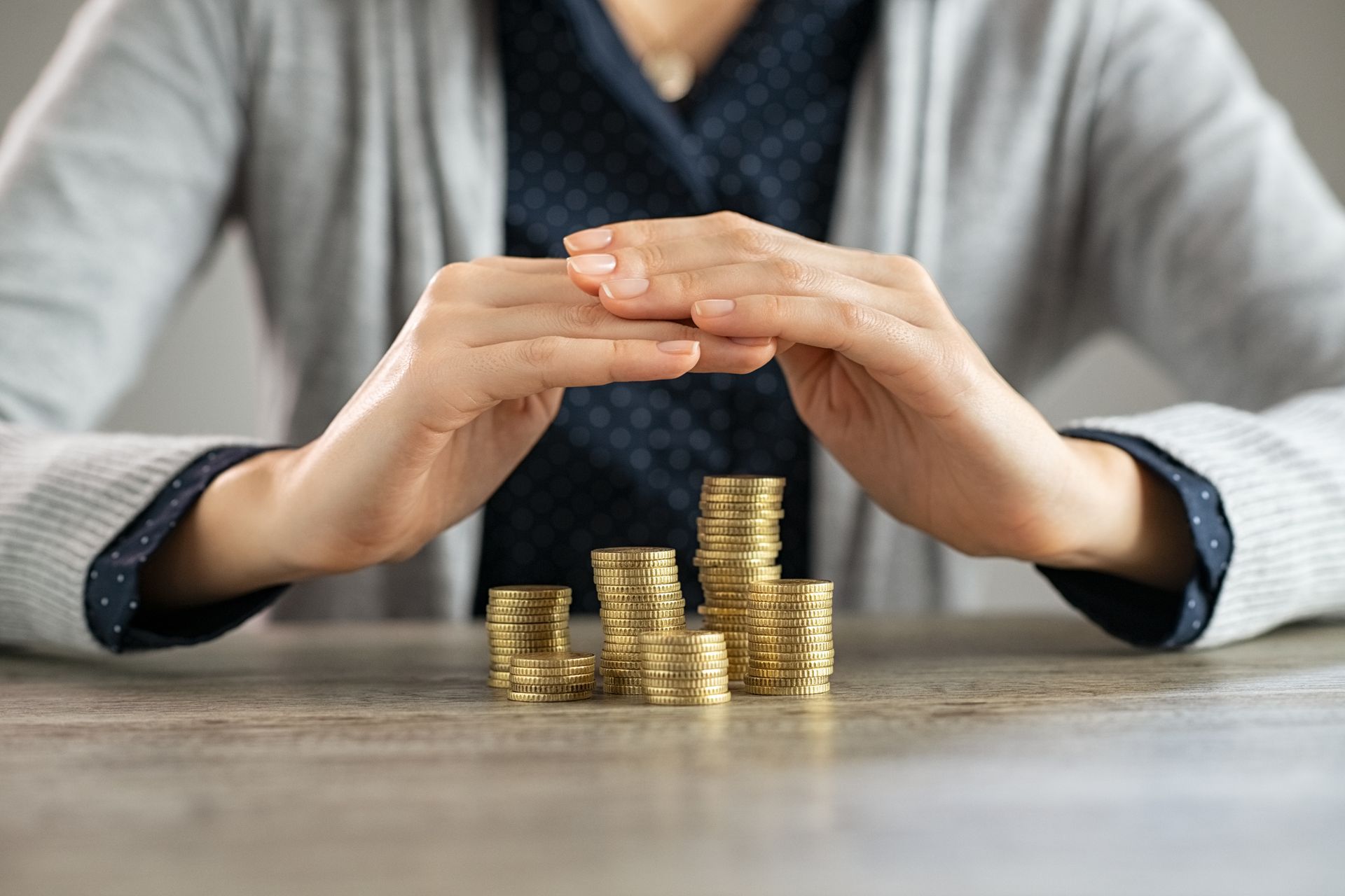 A woman is sitting at a table with stacks of coins in her hands.