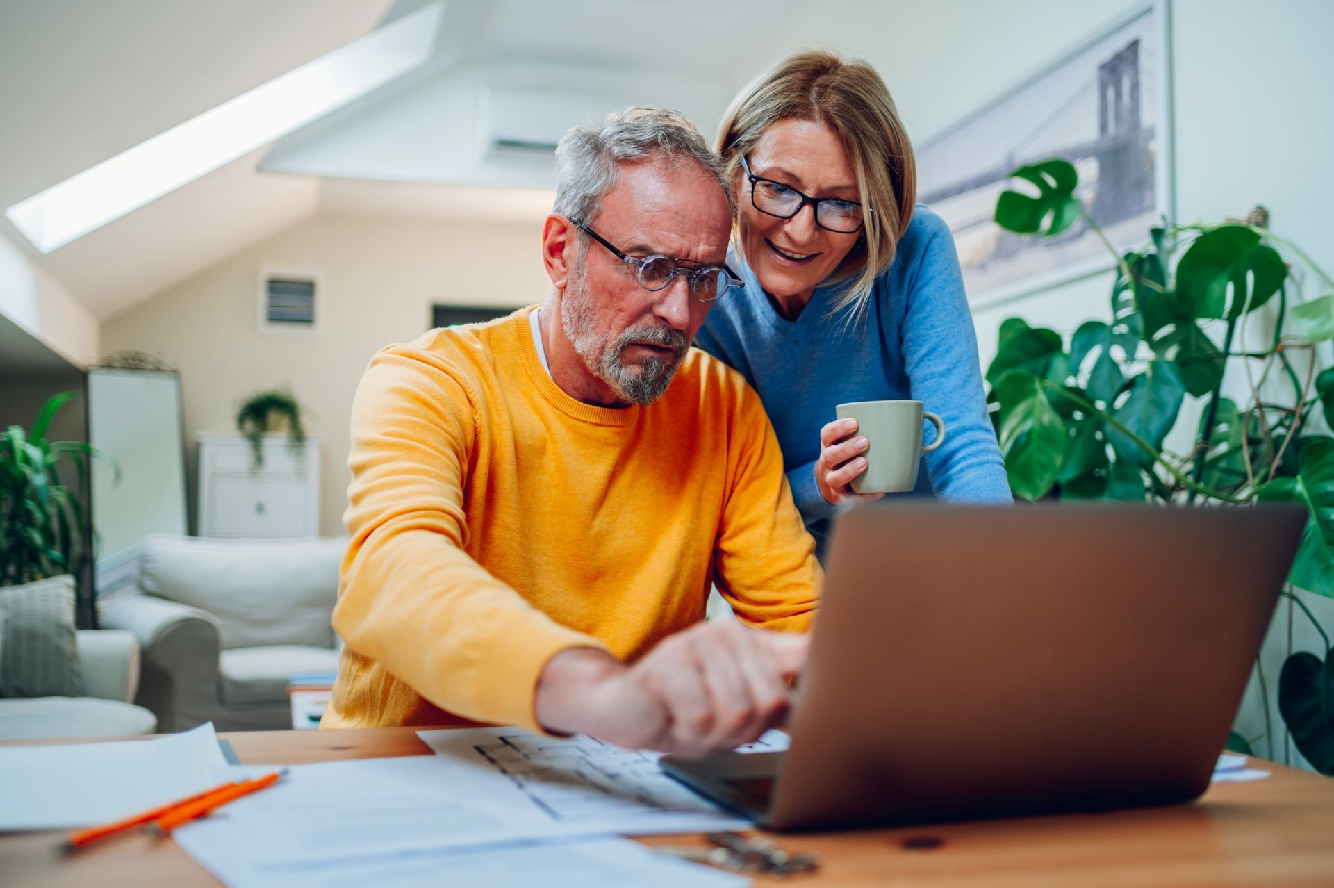A man and a woman are looking at a laptop computer.