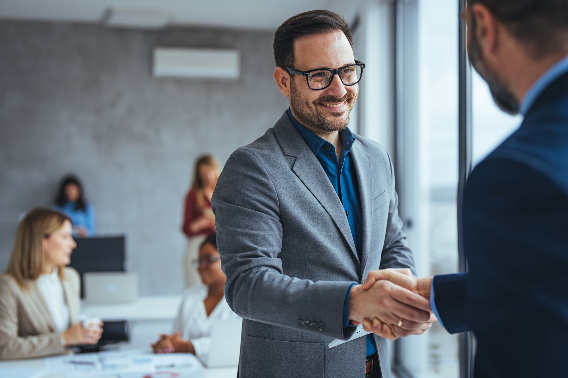 A man in a suit is shaking hands with another man in an office.