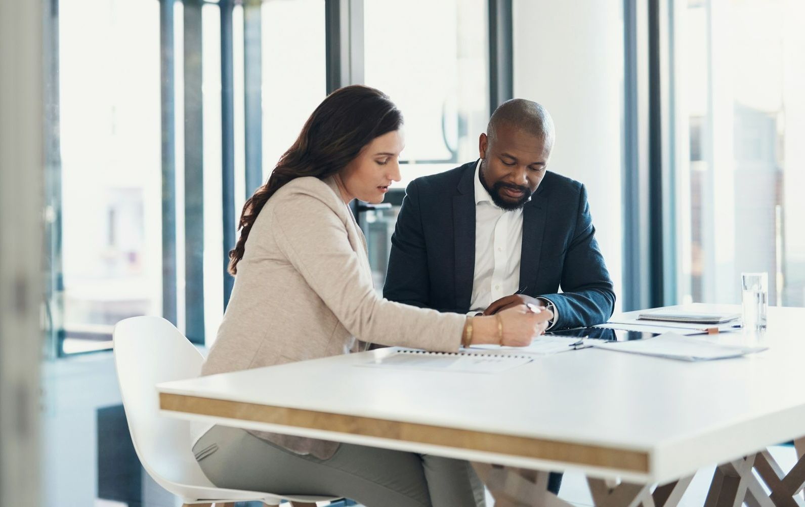 A man and a woman are sitting at a table looking at a piece of paper.