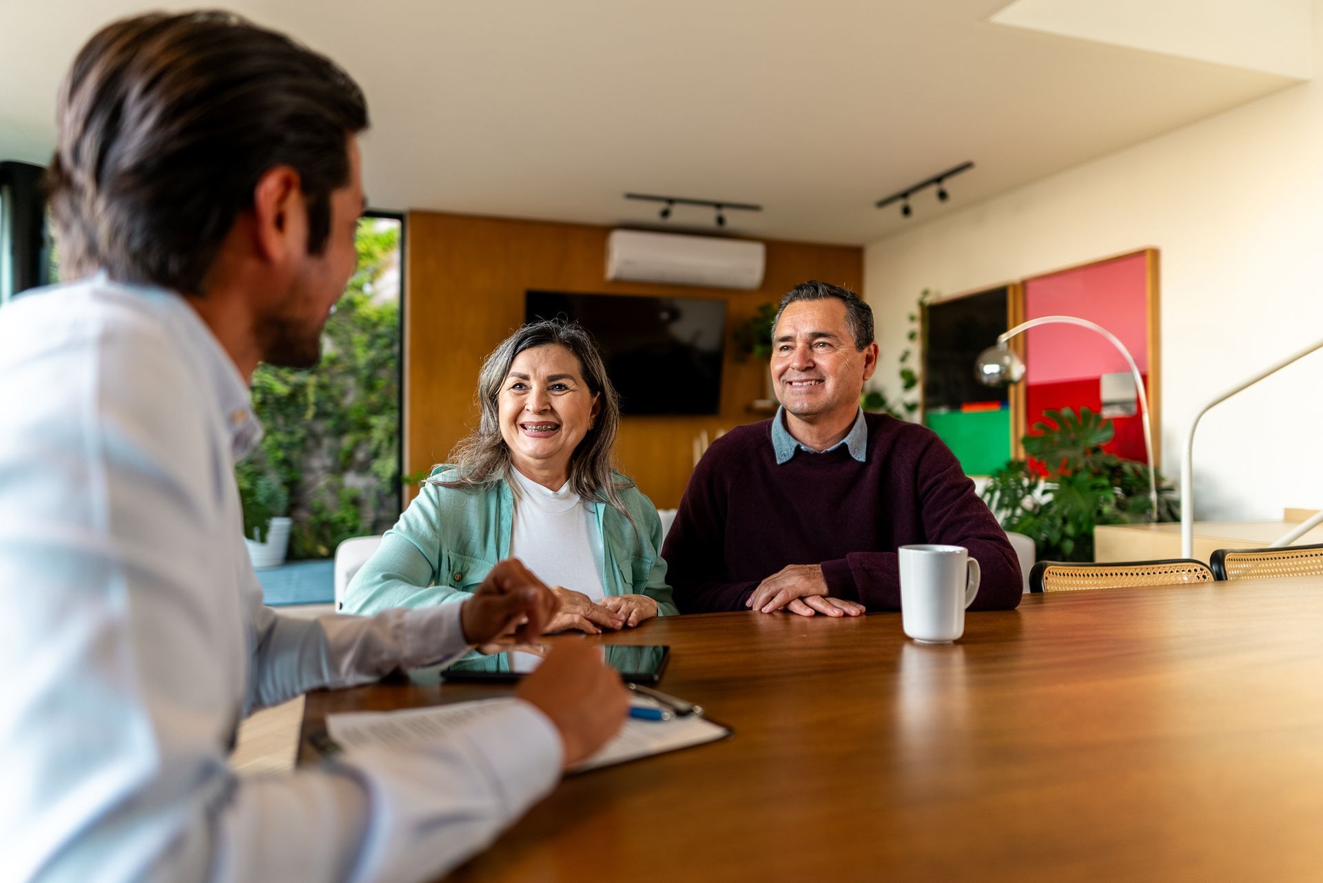 A senior couple talking to a financial security advisor at their house.