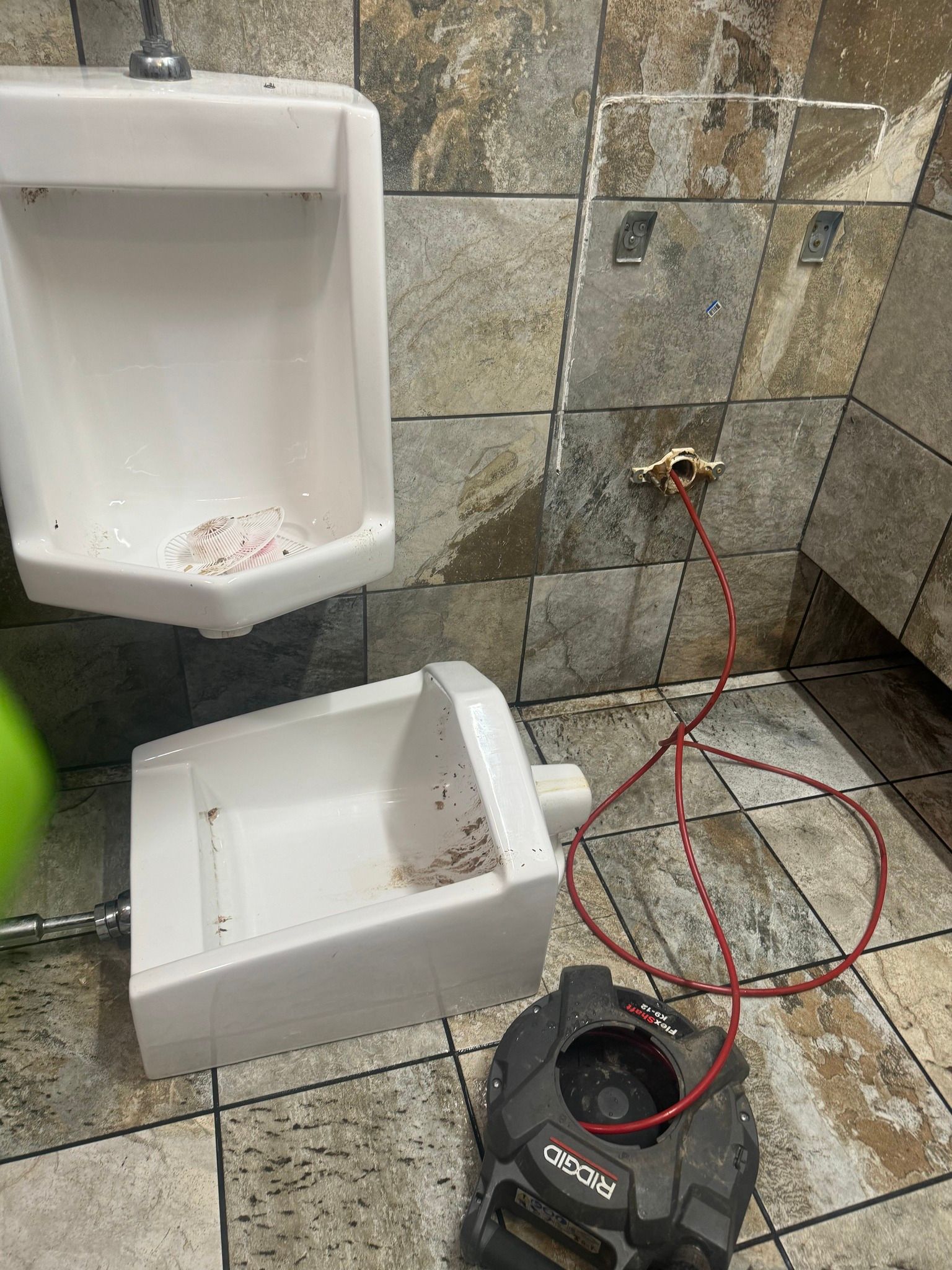 A toilet and urinal in a bathroom with a camera attached to it.